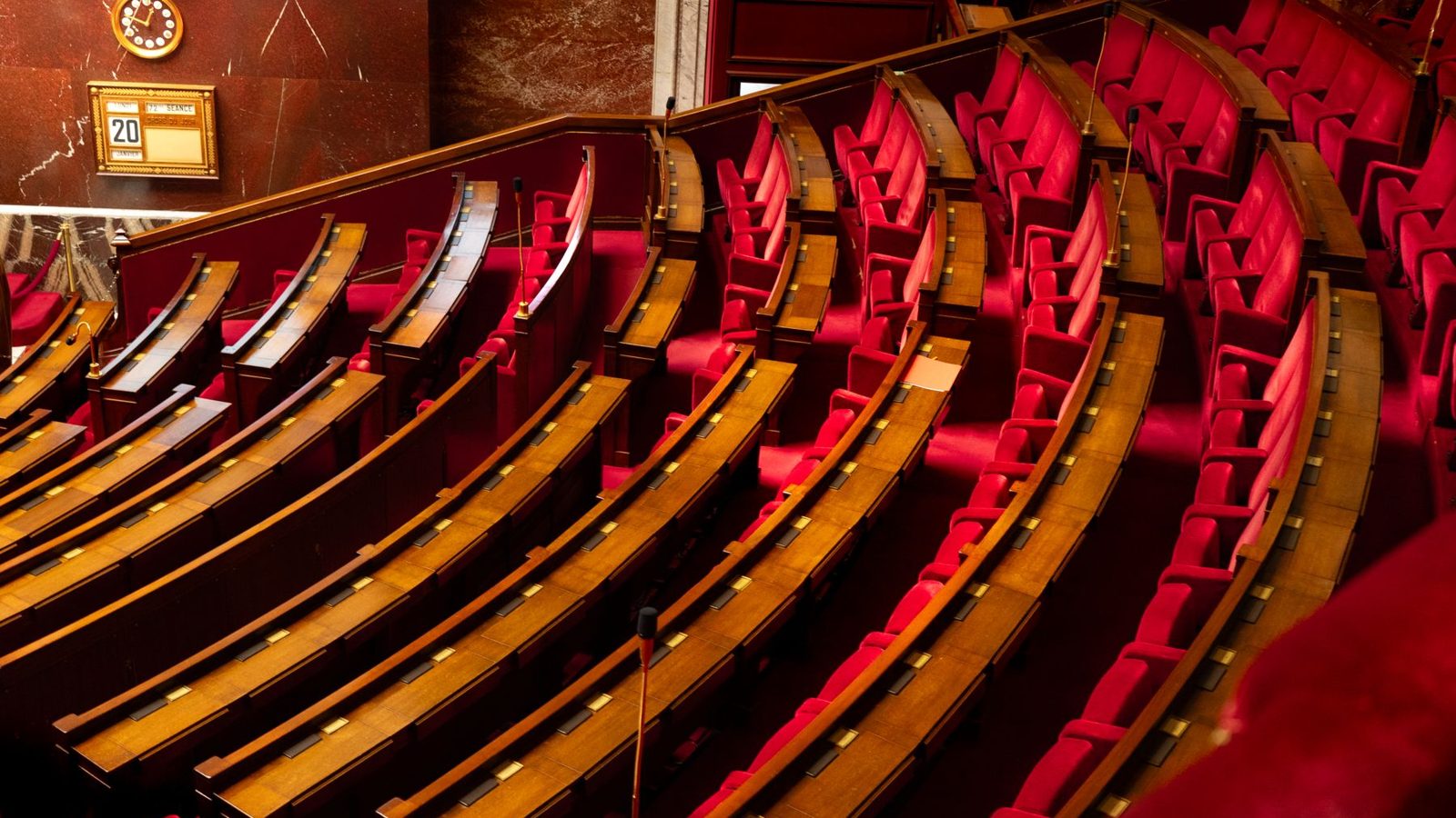 Travées vides de l'hémicycle, banquettes rouges et pupitres